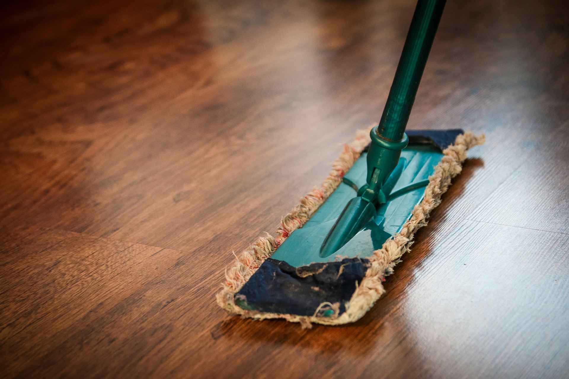 A green mop on a hardwood floor