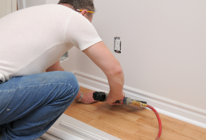 A man working with a nail gun to install new laminate floors
